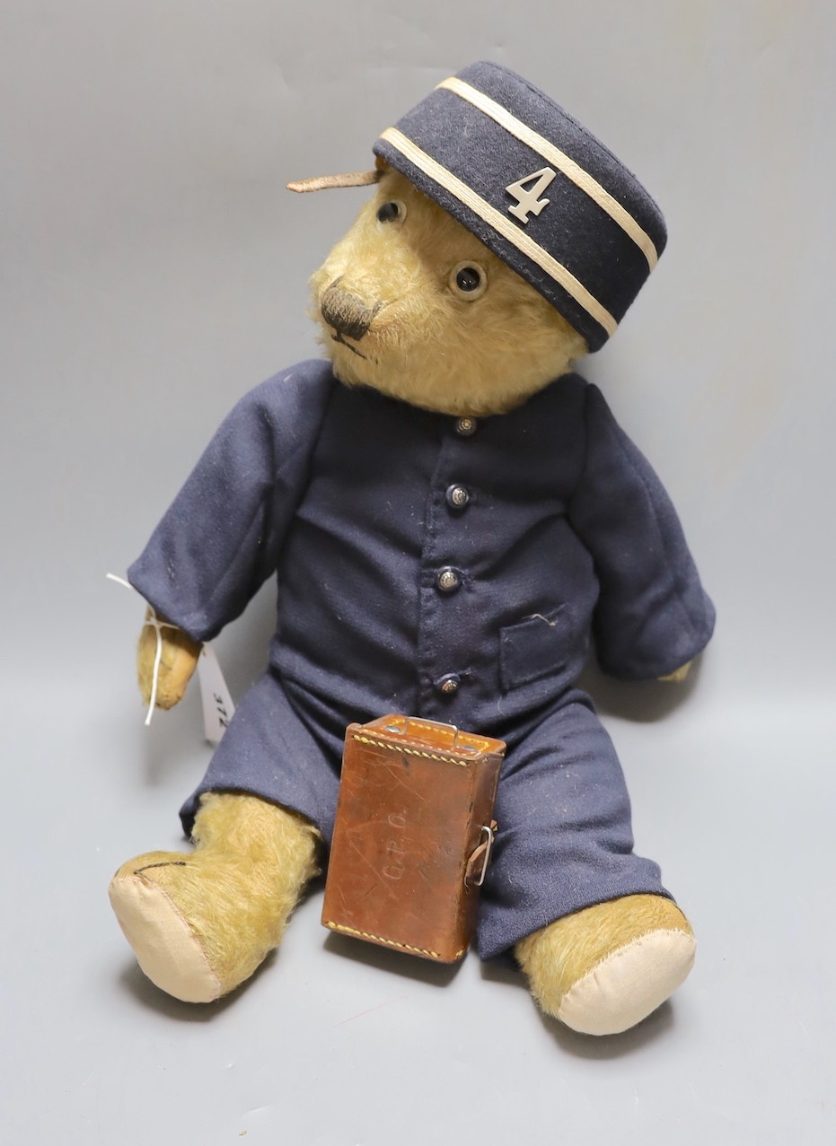 A Chiltern teddy bear dressed as railway porter, replaced footpads, thinning of mohair to tummy and arms together with miniature leather trunk